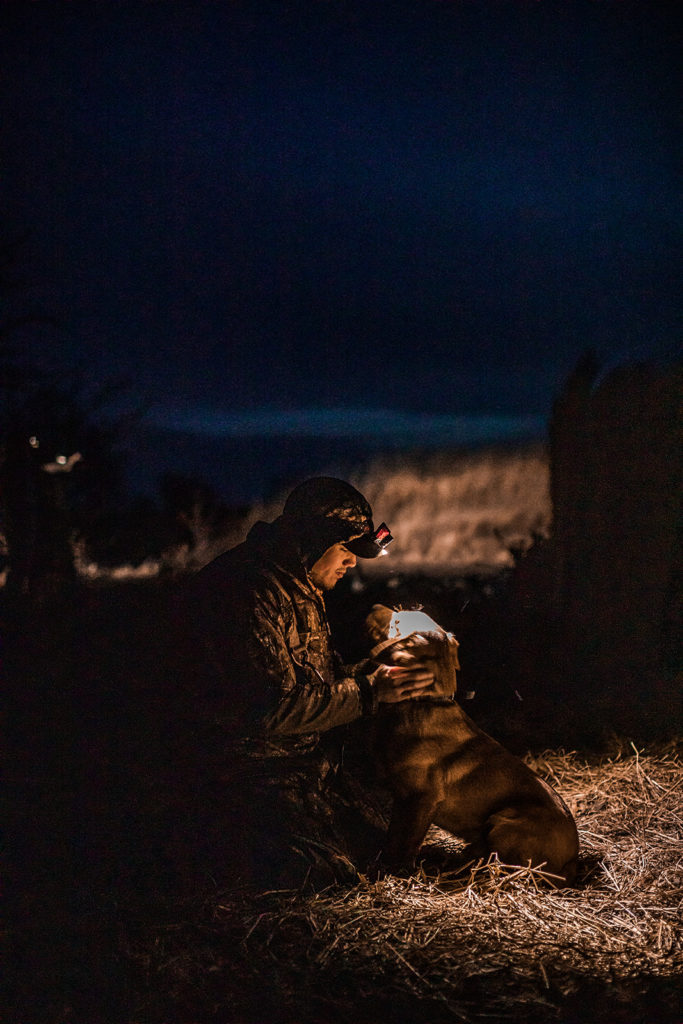 Kansas hunter petting his dog. 